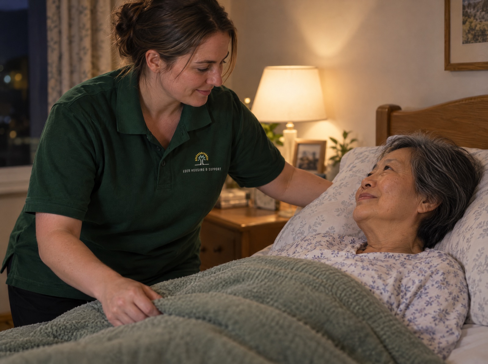 Eden night carer settling an older woman comfortably in bed at home in Telford